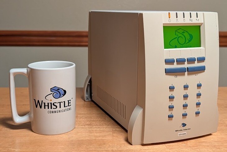 An InterJet 200 running NetBSD 11.0, beside an original Whistle Communications mug.